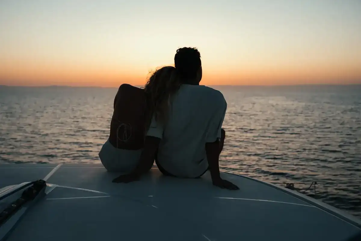 A couple watching the sunset from the bow of a Lagoon